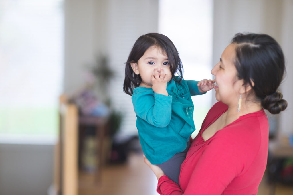 Native American mom holding daughter in their living room